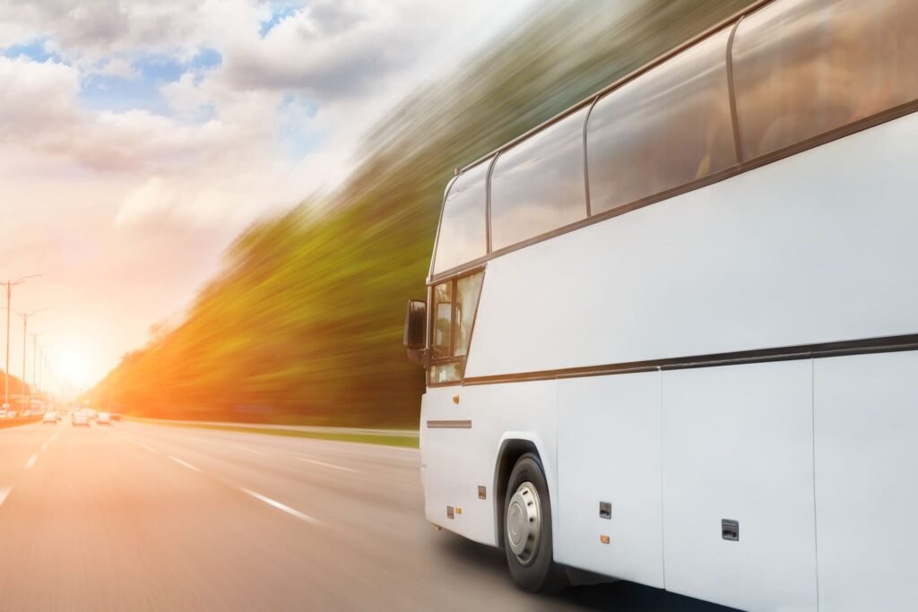 Big luxury comfortable tourist bus driving through highway on bright sunny day. Blurred motion road.