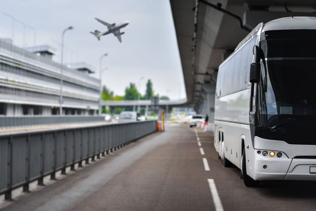A white shuttle bus driving to the airport for passenger pickup.