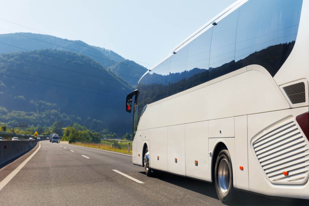 A luxury white charter bus drives towards the Catskills, New York. Scenic view of moutains and open road.