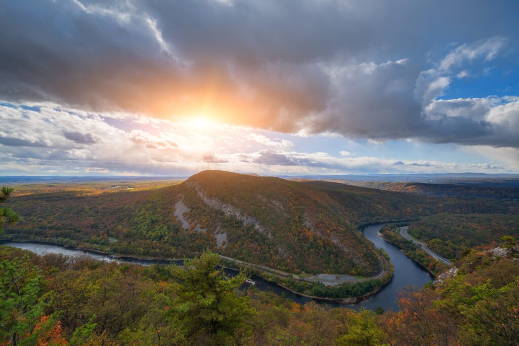Mount Tammany is 1,527 feet tall. That sounds modest until you are on the Red Dot Trail, gaining about 1,200 of those feet in a mile and a quarter of rock steps. At the top the Delaware Water Gap opens up below you, the river bending south through the notch. Autumn is when that view pays the most. It is also when the lot at Dunnfield Creek fills before 8 a.m., and the shoulder of I-80 turns into a line of parked cars. Our coach leaves Manhattan and drops you at the trailhead instead. Quick Summary: Key Takeaways The climb: about 1,200 feet of gain in 1.2 miles on the Red Dot Trail, then an easier Blue Dot descent for a 3.5-mile loop. Peak color: mid-to-late October is the usual window in the Delaware Water Gap, with the ridge turning before the valley floor. Parking is the problem: the Dunnfield Creek lot off I-80 Exit 1 fills before 8am on fall weekends. The day trip runs $49: the Mount Tammany trip pairs the hike with a smokehouse barbecue stop on the way back. Groups can go private: a charter coach works for hiking clubs, offices, and family groups who want their own departure time. Mount Tammany packs real climbing into a 3.5-mile loop This is a short hike that hikes hard. The Red Dot Trail gains about 1,200 feet in roughly 1.2 miles, mostly over uneven rock, and the last third is closer to a scramble than a walk. Come down the Blue Dot. It is gentler; it drops you along Dunnfield Creek, and taking the loop in that direction means you climb the hard part fresh instead of picking your way down it on tired legs three hours later. Budget three to four hours of moving time. Add a half hour at the summit, because nobody leaves that view quickly. → the Mount Tammany bus trip from Manhattan Foliage in the Delaware Water Gap peaks mid-to-late October The ridge turns before the river. Color usually reaches the top of Tammany in the second week of October, then works down toward the valley floor over the following ten days. The Delaware Water Gap National Recreation Area draws more than 4 million visits a year, according to the National Park Service, and a healthy share of those arrive in October. Plan around the crowd rather than hoping it stays home. Early October still delivers. Late October can be better, with thinner crowds, colder air, and long light on the rock. → check the current trip schedule The parking lot is the real reason to take the bus Dunnfield Creek has a small lot. On an October Saturday, it is full before 8am, and the overflow parks along the ramp at I-80 Exit 1 in a way that makes rangers unhappy and drivers late. A coach skips that entirely. You board in Manhattan, eat a bagel for ninety minutes, and step off at the trailhead with your boots already laced. The ride home is the other half of it. After 1,200 feet of climbing, sitting in a climate-controlled seat while somebody else handles the westbound merge onto I-80 is worth more than most people expect it to be. → private charter buses for group hikes Dress for a ridge, not for the city The summit runs 10 to 15 degrees colder than Manhattan, and wind on exposed rock does the rest. Layers, a wind shell, and gloves once you get into late October. Footwear decides the day. The Red Dot is loose rock and roots for most of its length, and sneakers with worn tread turn a fun scramble into the kind of slow, careful descent that nobody enjoys and everybody remembers. Bring two liters of water. No tap up there. → trip questions and gear answers Autumn has more than one day trip out of the city Tammany is the headline, not the only option. Resorts World Catskills and Wind Creek both run as $49 day trips through the fall, which suits people who want the drive through the mountains without the 1,200-foot climb attached to it. Groups get more freedom. A private charter lets a hiking club, an office or an extended family set the departure time, the pickup point, and the return, anywhere within about 300 miles of New York City. Ski season follows fast. Belleayre, Hunter, and Windham dates start moving in November. → browse all trips leaving New York City Thirty years of running buses out of Manhattan shows up in the logistics We have been doing this since the early 1990s, and the boring parts are where the experience shows. Departures leave on time, dispatch answers the phone from 9am to 9pm daily, and the exact pickup spot arrives in your confirmation email so nobody is wandering around Union Square at 6:45am. Cancellations are simple. Full refund up to 24 hours out, plus weather reschedules or credits when a ridge is iced over. That policy exists because we would rather move your date than watch you hike something unsafe. Frequently Asked Questions Q: How hard is the Mount Tammany hike? A: Strenuous but short. The Red Dot Trail climbs roughly 1,200 feet in 1.2 miles over rock, with a scramble near the top. Most reasonably fit hikers finish the 3.5-mile loop in three to four hours. Trail shoes or boots matter more than fitness here. Q: When is peak fall foliage at the Delaware Water Gap? A: Usually mid-to-late October. The ridge tops turn around the second week, then color moves down toward the river over the next ten days or so. A warm, wet September tends to push the whole thing later. Q: Is there a bus from NYC to Mount Tammany? A: Yes. Our Mount Tammany day trip departs from a Manhattan pickup point, runs about ninety minutes each way, and includes a smokehouse barbecue stop. The exact pickup location comes in your confirmation email a few days before the trip. Q: How early should I book a fall hiking trip from New York City? A: October Saturdays are the first to sell, so two to four weeks out is smart, and earlier if you need seats together. Private charters for clubs or offices need more lead time, especially on peak-foliage weekends. Grab a seat before the October dates close Check the schedule, pick a Saturday, and let the coach handle I-80. Hiking clubs and offices can charter their own bus and set the departure time. Urban Sherpa Travel — 209 W 42nd St, New York, NY 10036 Hours: Daily 9:00 AM – 9:00 PM Website: urbansherpatravel.com → contact us to hold seats for your group