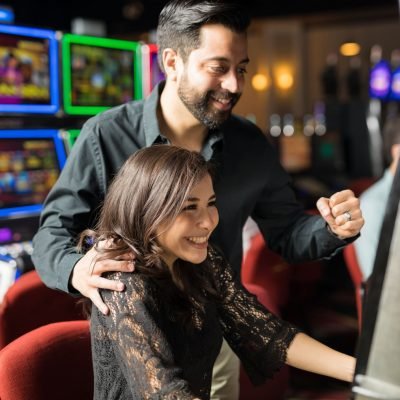 Portrait of an excited couple winning some money in a slot machine in a casino